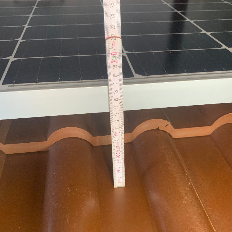 Aufbau einer Solaranlage mit Zollstock zur Höhenmessung vom Dachziegel bis zur Oberkante des Solarmoduls.